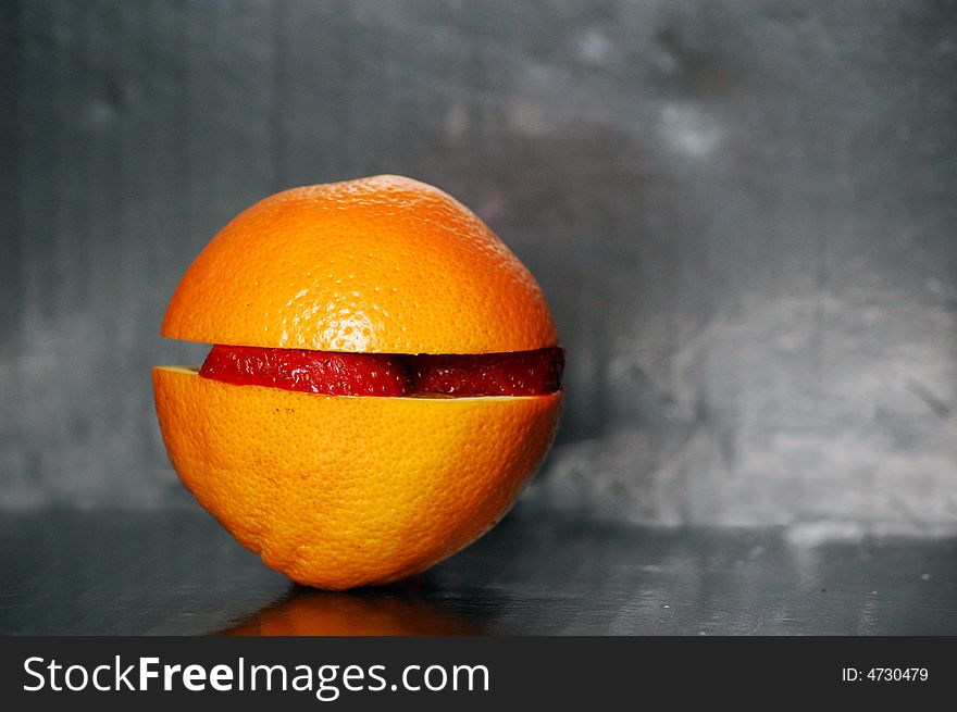 An orange and strawberry on black background. An orange and strawberry on black background