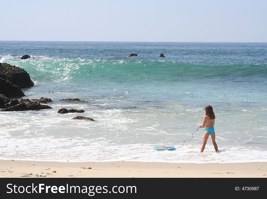 Young girl standing in the water with a boogie board. Young girl standing in the water with a boogie board.