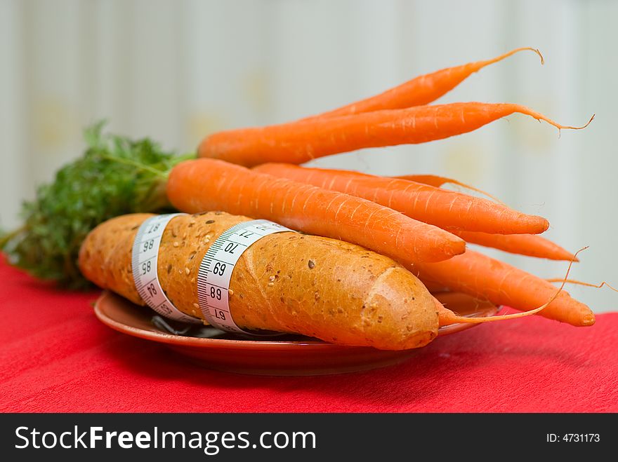 Bread roll and carrot on plate