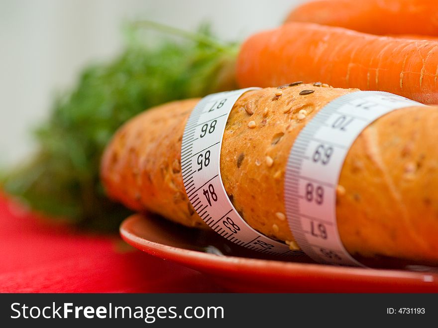 Bread roll and carrot on plate