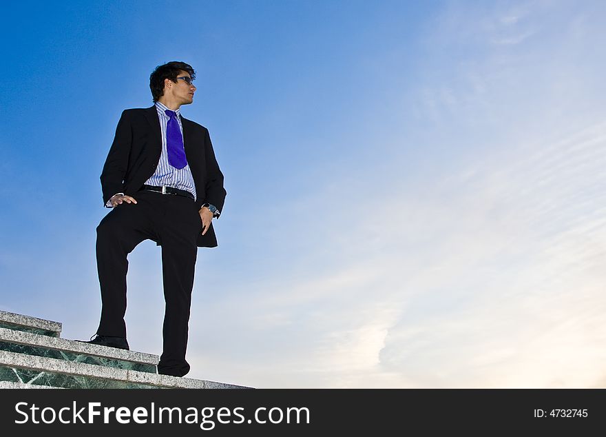 Businessman posing on stairs against blue sky. Businessman posing on stairs against blue sky.