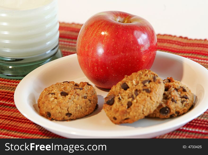 A plate of cookies, an apple and a glass of milk. A plate of cookies, an apple and a glass of milk.