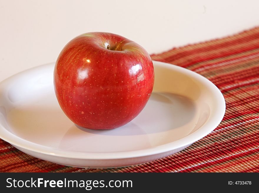 A red apple on a white plate. A red apple on a white plate.