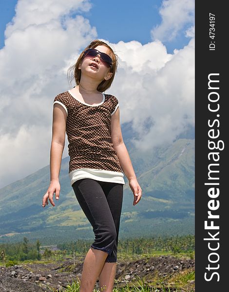 Girl standing behind Mayon volcano looks up into the sky at the clouds. Girl standing behind Mayon volcano looks up into the sky at the clouds