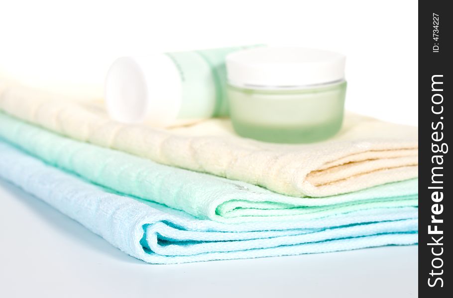 Three towels and cream on a white background. Selective focus. Three towels and cream on a white background. Selective focus.