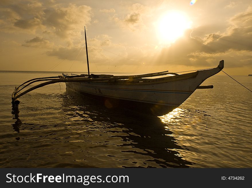 Banca boat at sunset moored on the beach after a busy day. Banca boat at sunset moored on the beach after a busy day