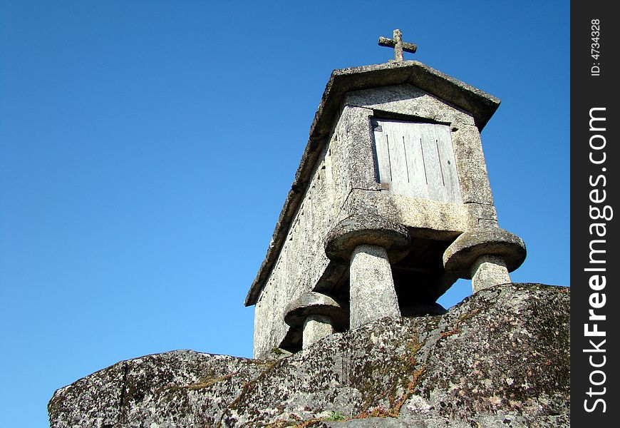 Espigueiro in the sun under blue sky over old stone used to drying corn in Soajo, Portugal. Espigueiro in the sun under blue sky over old stone used to drying corn in Soajo, Portugal