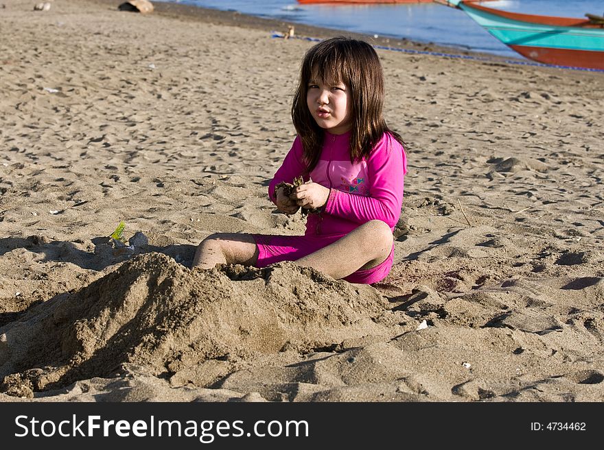 Girl playing with sand on the beach