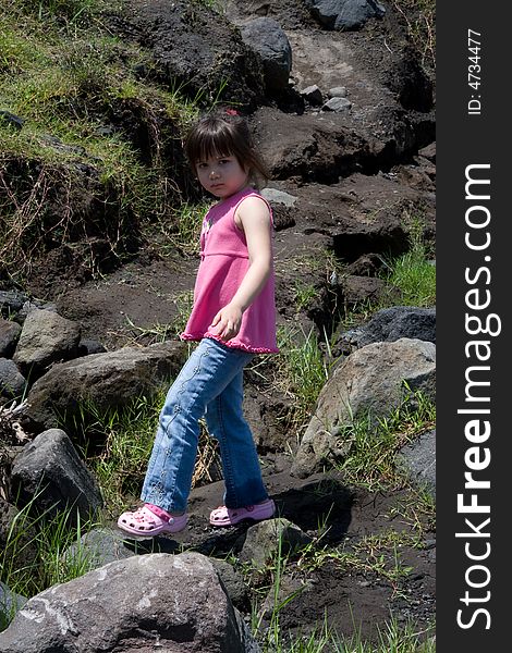 Girl walking across boulders laying on a hill. Girl walking across boulders laying on a hill