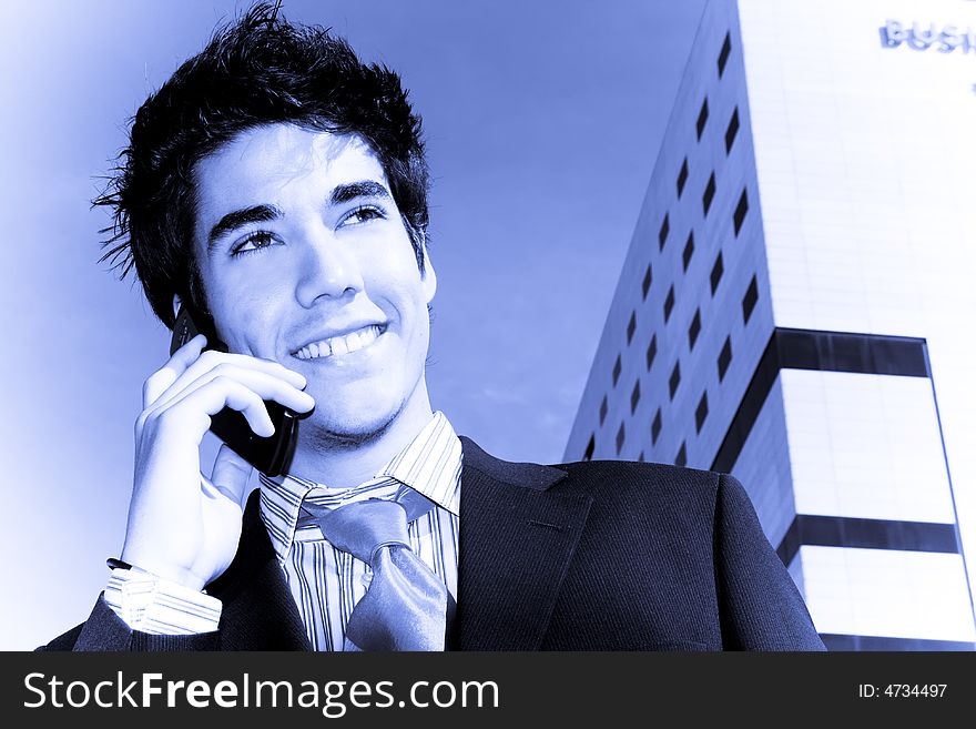 Businessman on phone over urban background, blue toned.