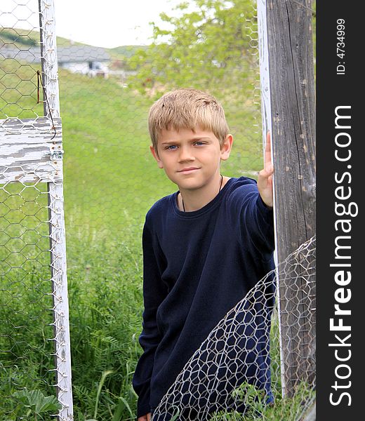 Boy standing in outdoor structure on farmland. Boy standing in outdoor structure on farmland.