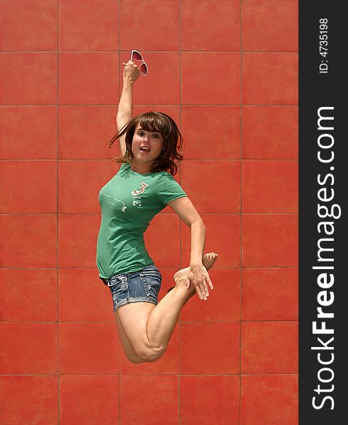 - a model jumps in front of a red wall. - a model jumps in front of a red wall