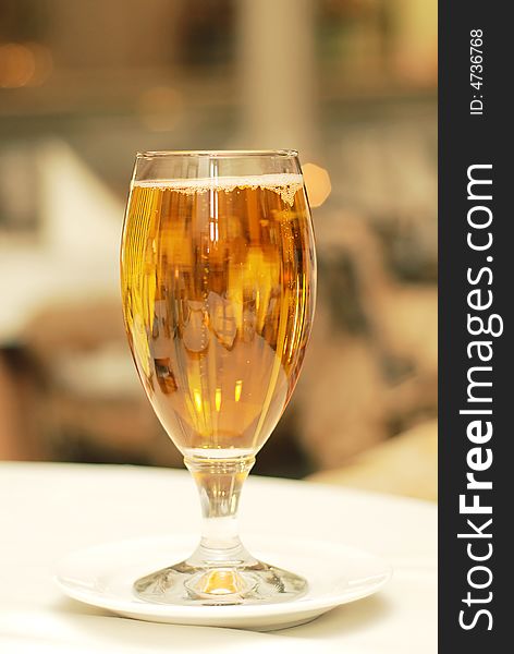 Glass of golden beer on table in restaurant with bubbles and reflections bokeh. Glass of golden beer on table in restaurant with bubbles and reflections bokeh