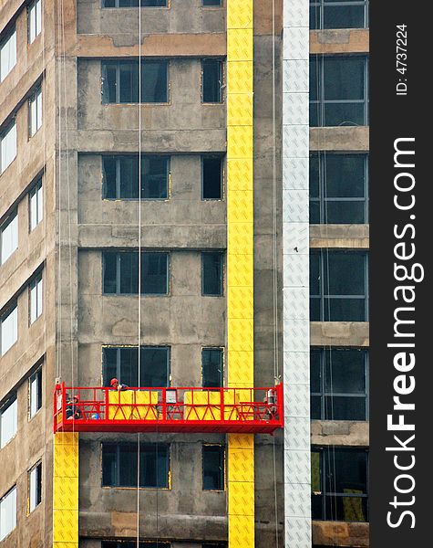 Workers decorated the ongoing construction of the external walls of high-rise buildings, the installation of yellow ceramic tile. Workers decorated the ongoing construction of the external walls of high-rise buildings, the installation of yellow ceramic tile.