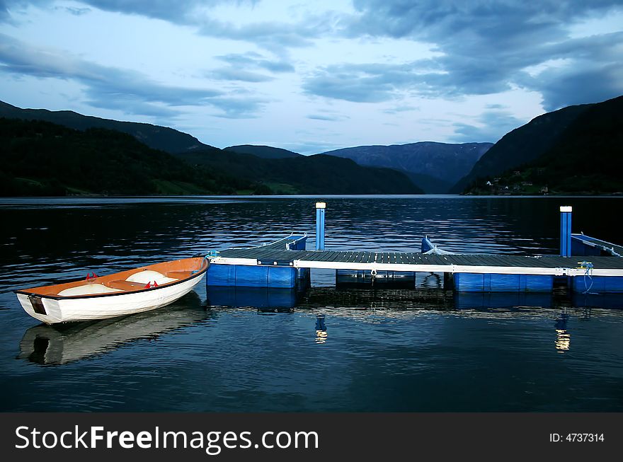 Small boat in beautiful Norwegian fjord at the dusk - silent scenics. Small boat in beautiful Norwegian fjord at the dusk - silent scenics