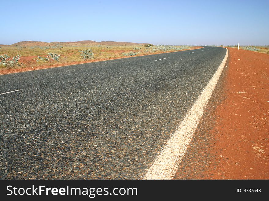 Typical Australian road with red dirt and arid landscape. Australia.