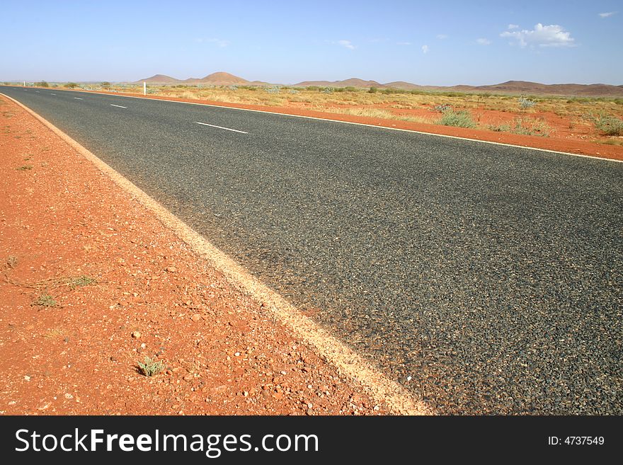 Typical Australian road with red dirt and arid landscape. Australia.