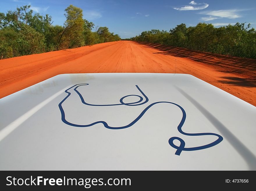 Red Australian rural road with blue sky. Perspective from the car hood. Copy space. Red Australian rural road with blue sky. Perspective from the car hood. Copy space.