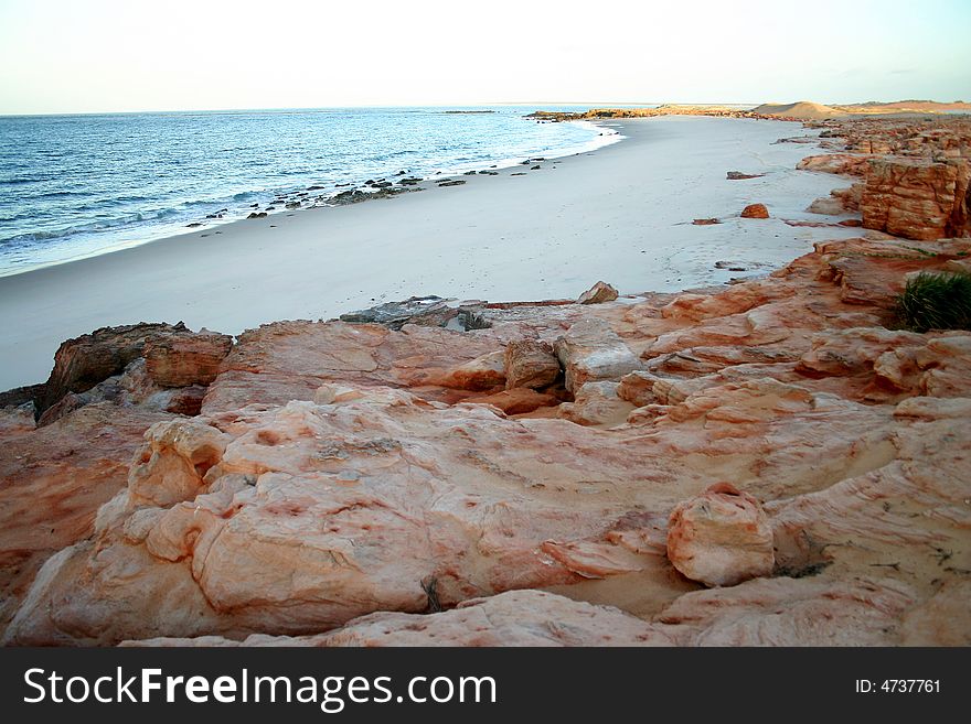 Red rocks over the long sandy beach. Australian. Red rocks over the long sandy beach. Australian
