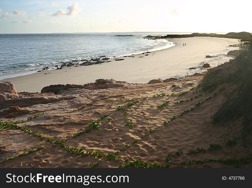 High angle shot over the sandy beach with two people walking in background. Australian. High angle shot over the sandy beach with two people walking in background. Australian