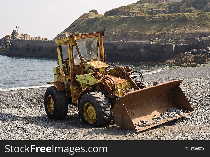 An old tractor on a shingle beach in Cornwall, UK. An old tractor on a shingle beach in Cornwall, UK