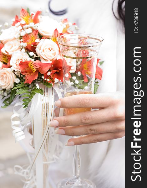 Hand of bride holding glass of champagne. Low DOF, focus on glass. Hand of bride holding glass of champagne. Low DOF, focus on glass
