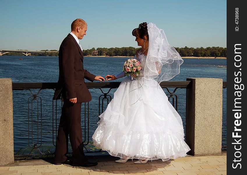 Newly wedded couple walking on near the river