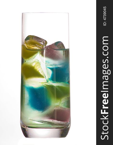 A glass of clear water and colored ice cubes over a white background