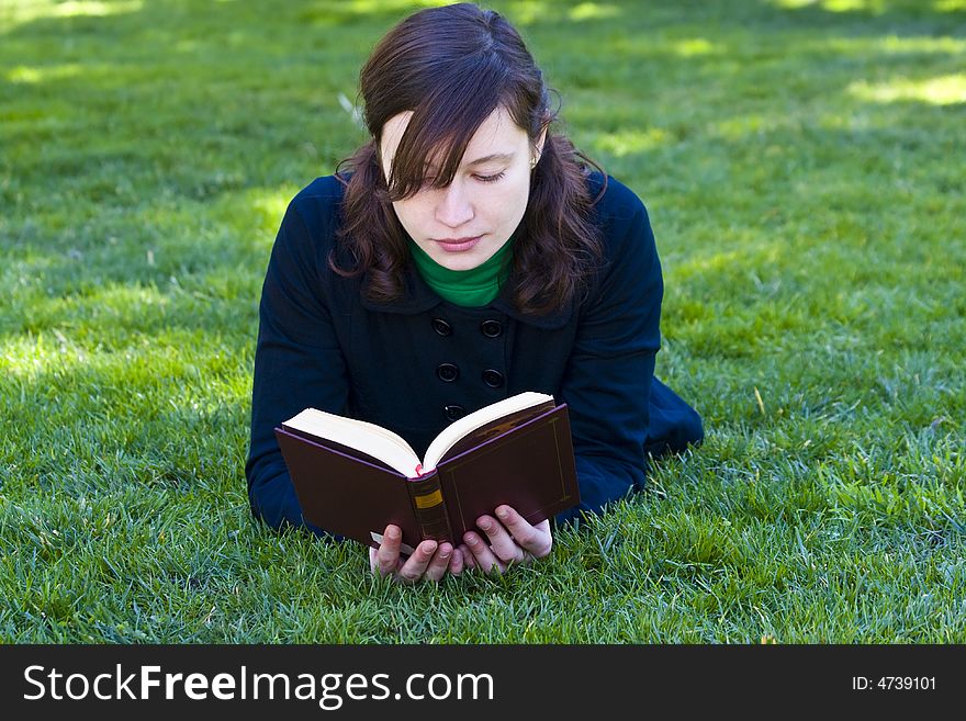 Beautiful brunette woman reading on the grass