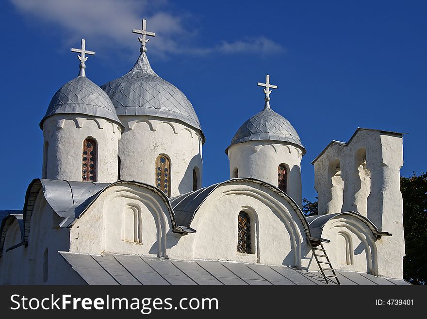 On a photo domes of the church on a background of the blue sky with a cloud. Russia, Pskov, summer day.