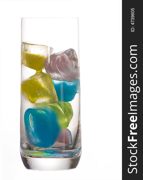 A glass of colored ice cubes over a white background. A glass of colored ice cubes over a white background