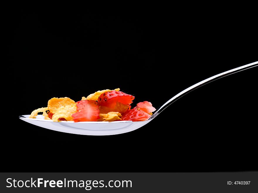 Closeup of cereal with strawberries on a spoon on a black background