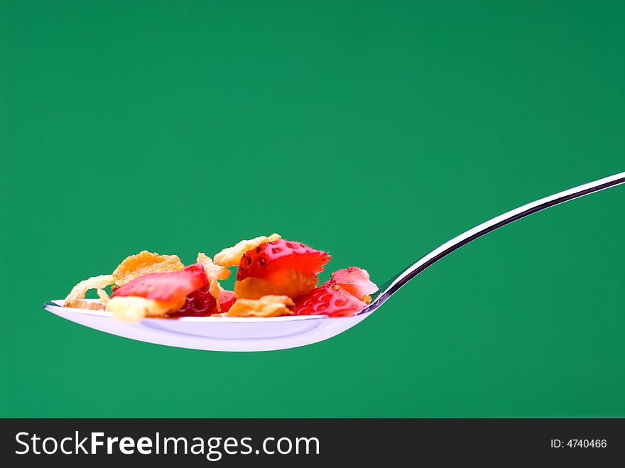 Closeup of cereal with strawberries on a spoon on a stricking green background