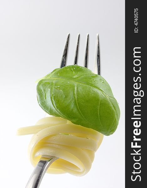 A fork with tagliatelle and a leaf of basil