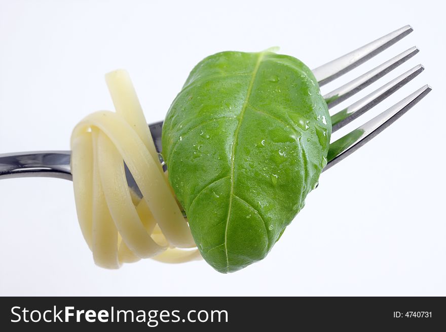 Tagliatelle on a fork with a basil leaf