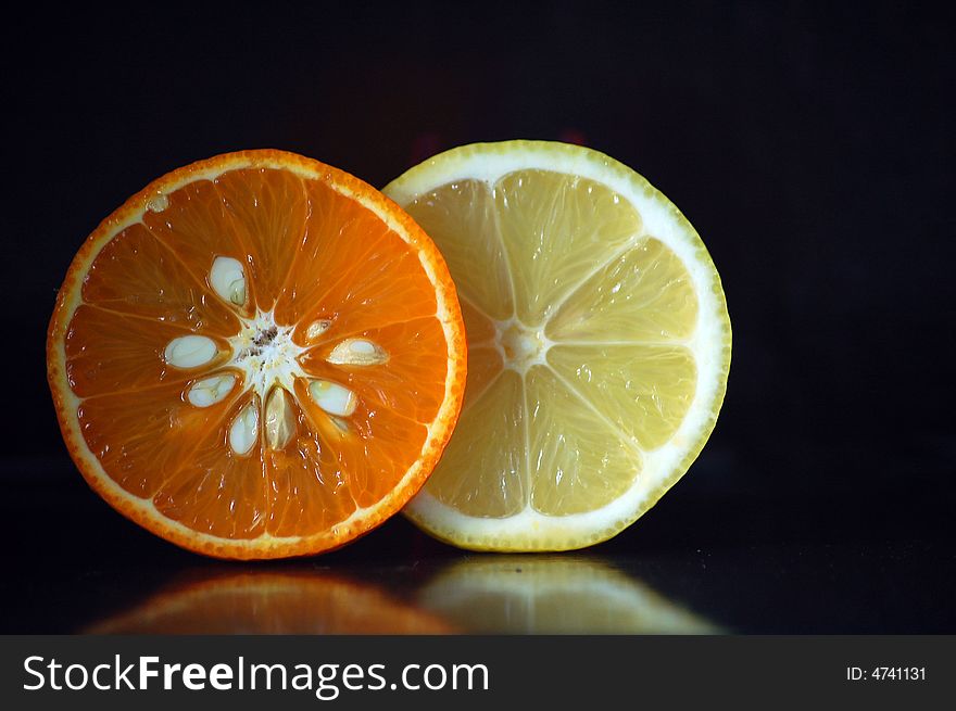An orange and lemon on black background. An orange and lemon on black background