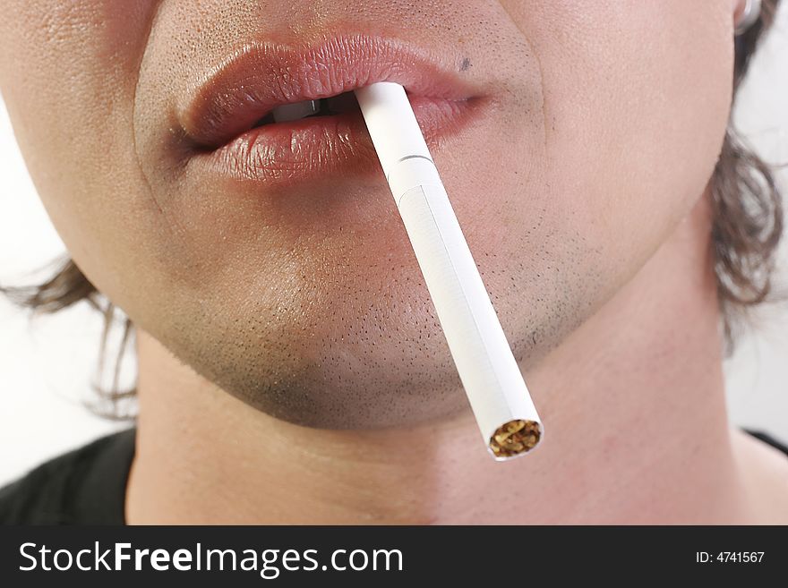 Young man holds a cigarette in mouth
