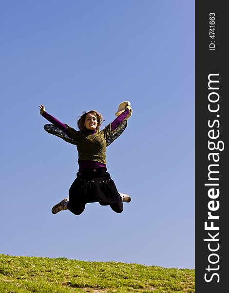 Happy young woman jumping over the grass