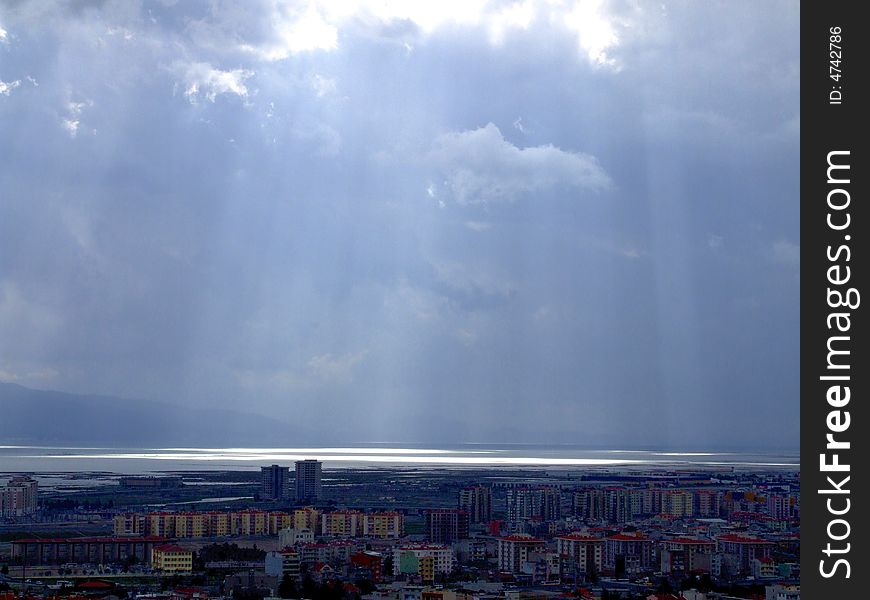 Sunshine amoung clouds compose spotlignt on the sea.