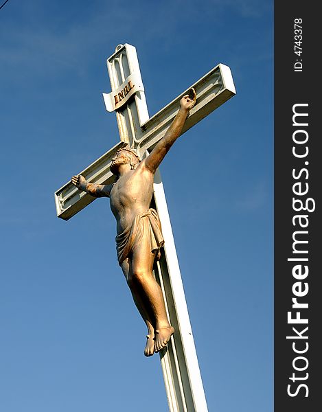 Realistic statue of Christ on the cross against blue sky. Realistic statue of Christ on the cross against blue sky