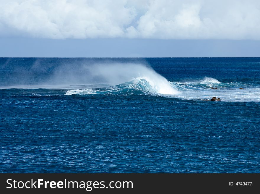 Crashing waves off Hawaii in strong wind resulting in blowing spray. Crashing waves off Hawaii in strong wind resulting in blowing spray