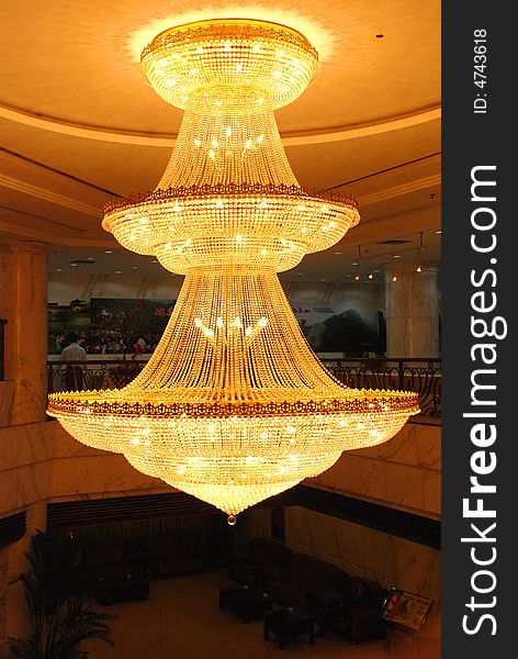 A big golden pendant lamp in a hotel lobby hung from the wood ceiling.