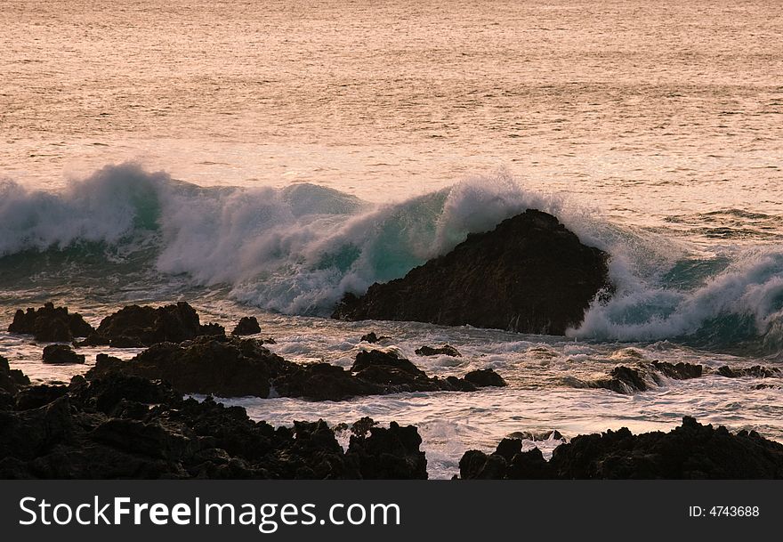 Crashing waves on rock in sunset