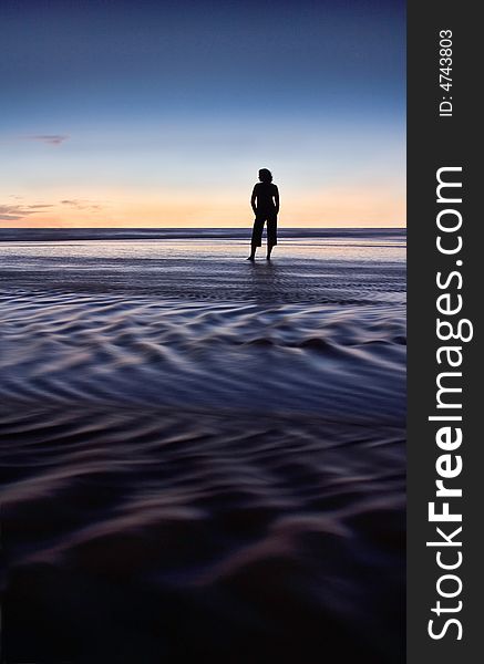 Woman relaxing on the beach , silhouetted against the sunset sky. Woman relaxing on the beach , silhouetted against the sunset sky.