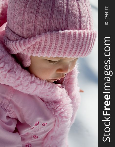 Young girl dressed in pink hat and coat outside in the snow. Young girl dressed in pink hat and coat outside in the snow.