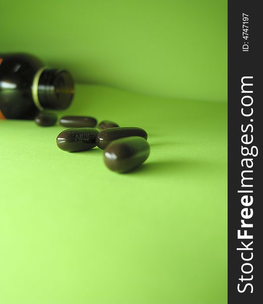 A bottle of pills on a green background