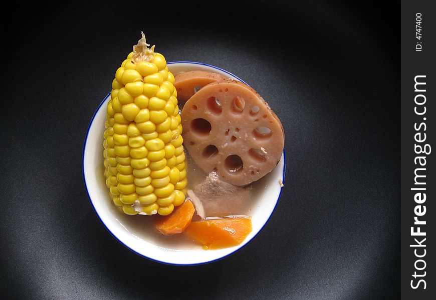 Top view for a bowl of soup with lotus, corns, carrot and meats