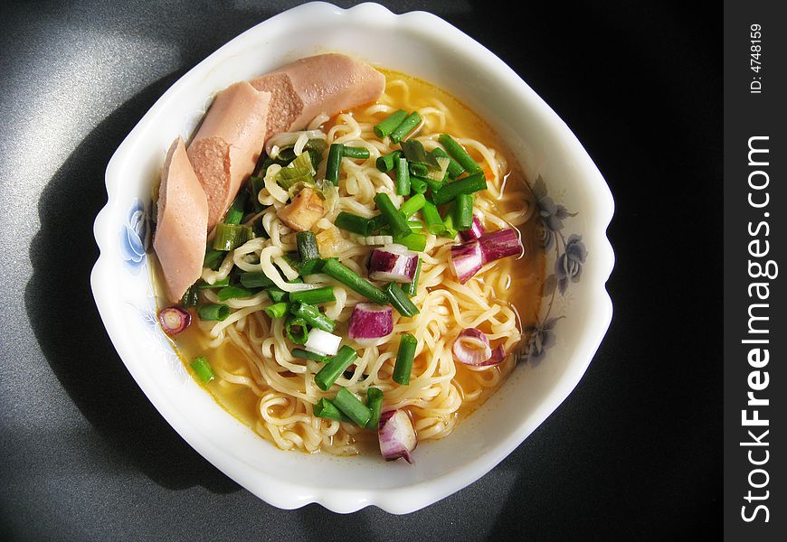 Top view for a bowl of instant noodles with spring onion and sausage