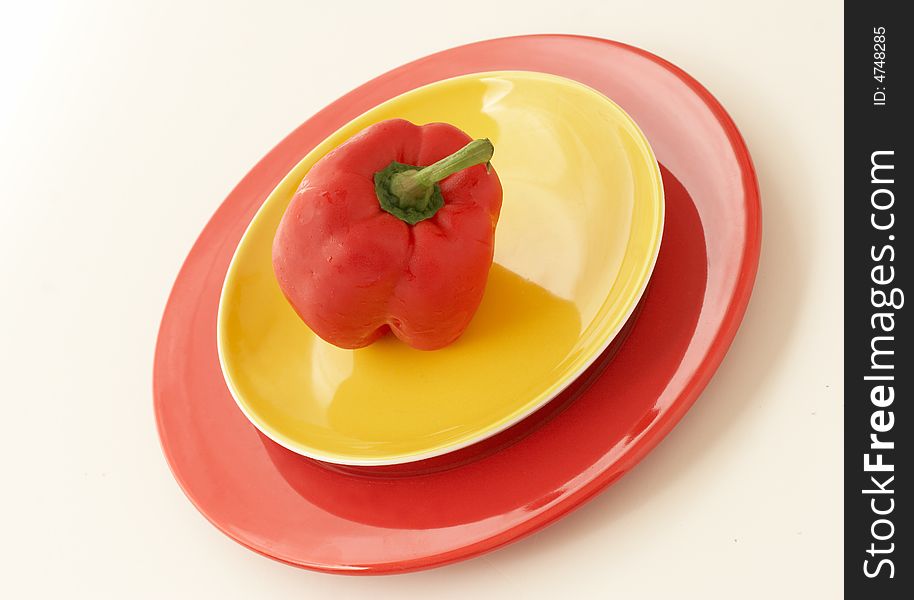 Red pepper on a yellow and red plates. Red pepper on a yellow and red plates
