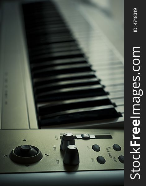 Side view of electronic synth keyboard with knobs and sliders. Side view of electronic synth keyboard with knobs and sliders.